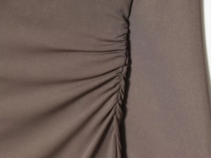 Detailed macro view of brown elastic knit fabric featuring side ruched pleated stitching