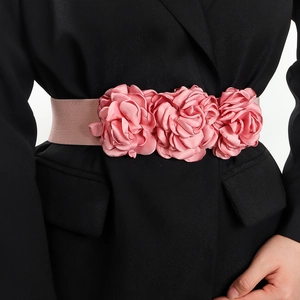 Pink elastic waist belt featuring three large fabric rose flowers worn over a black blazer