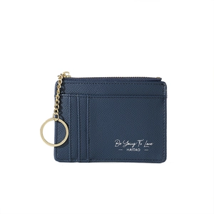 Detail of navy blue textured leather card holder with gold keychain and zipper pocket