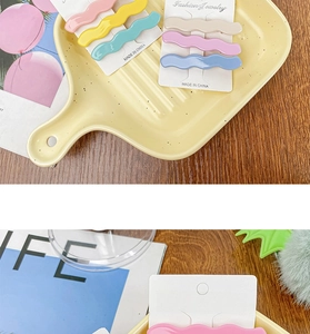 Macro detail of wave-shaped macaron acetate hair clips in a stylish ceramic tray