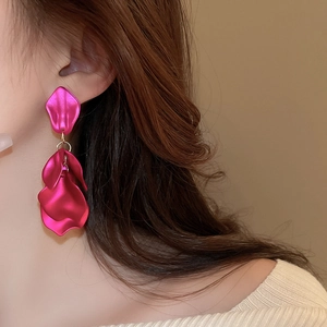 Detailed close-up of rose red leaf petal drop earrings worn on a female model