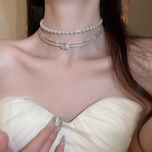 Detail of layered pearl and sparkling rhinestone choker necklace on model's neckline