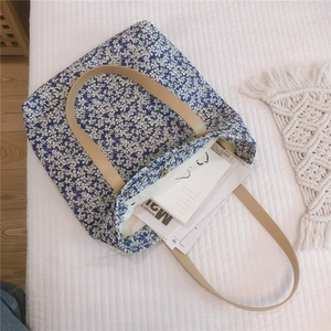 Blue floral canvas tote bag with brown leather straps shown with magazines inside