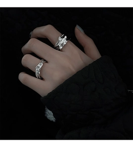 Close-up of two irregular silver liquid metal rings worn on hand in dark lighting