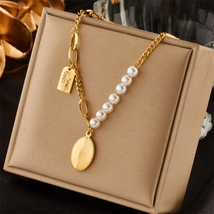 Detail of gold chain necklace with white pearls and oval pendant on a leather box