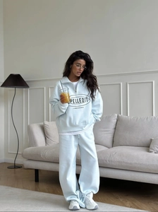 Detail of light blue tracksuit showing half-zip hoodie and wide-leg sweatpants set