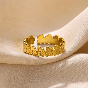 Detailed close-up of a gold floral pattern adjustable ring on beige silk background