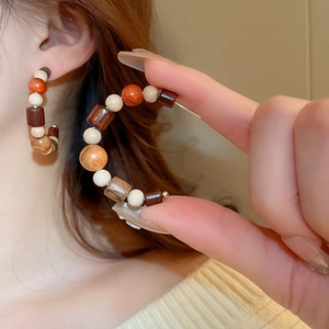 Macro detail of bohemian hoop earrings made of assorted brown wooden beads on a model