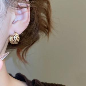 Gros plan de boucles d'oreilles C dorées vintage avec motif léopard sur un modèle
