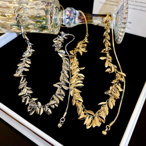 Dettaglio di collane con nappe a foglia oro e argento in una confezione regalo