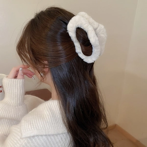 Close-up of a white plush hair claw clip worn on a woman's head for an autumn winter style