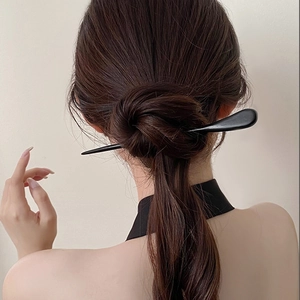 Détail d'un pic à cheveux noir minimaliste en bois porté avec un chignon de style chinois