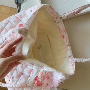 Detail der gesteppten Baumwolltasche mit Kirschmuster und Innentasche mit Reißverschluss