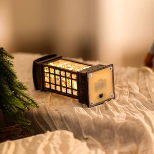 Detail of Christmas lantern with snowman and warm glow on soft white fabric background