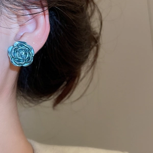 Close-up of elegant blue rose earring with pearlescent finish on model ear