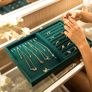 Vintage green velvet jewelry tray displaying gold necklaces and rings in organized slots