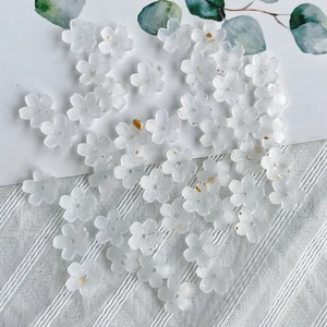 Close-up of translucent white resin flower beads with gold accents for jewelry making