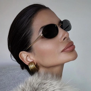 Chic rimless oval sunglasses with gold metal temples and chunky textured hoop earrings