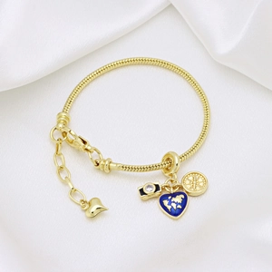 Detail of gold camera and blue heart world map charms on a snake chain bracelet