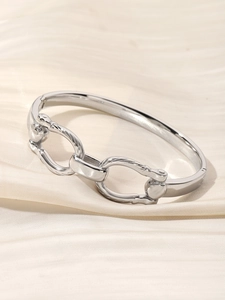 Detailed view of silver-tone double ring interlocking bangle on cream silk fabric