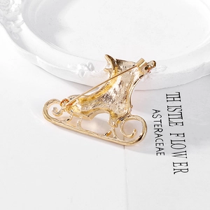 Back view of gold Christmas skate brooch showing brushed metal texture and pin fastener