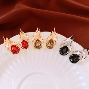 Detailed view of vintage teardrop earrings in red, black, and champagne stone on white tray