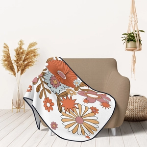 Bohemian floral flannel throw blanket in vintage warm tones draped over a brown sofa