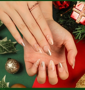 Macro detail of long stiletto press-on nails with golden snowflake and glitter gradient
