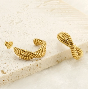 Detailed view of 18K gold plated C-shape twist hoop earrings on marble stone