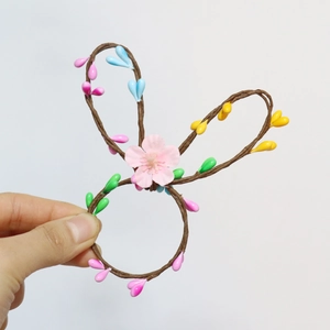 Detailed view of woven rabbit ear napkin ring with pink flower and colorful beads