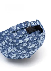 Detail of denim baseball cap showing adjustable metal buckle and floral pattern print