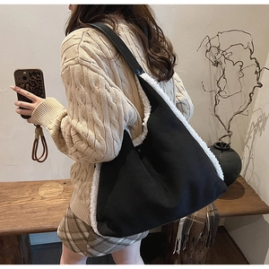Detailed view of large black tote bag with white faux fur trim on a model shoulder