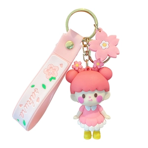 Pink Sakura girl doll keychain with floral strap and golden ring on white background