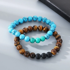 Detail of beaded bracelets with turquoise, tiger eye, and matte black stones on grey surface