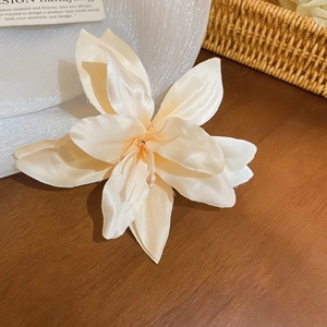 Detailed view of a cream fabric lily hair clip on a vintage dark wood table background