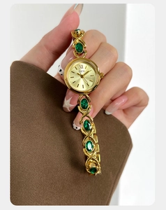 Détail de la montre bracelet dorée avec cristaux émeraude et cadran à effet soleil
