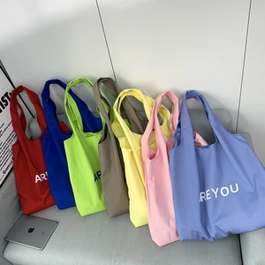 Close-up of colorful canvas tote bags with 'ARE YOU' text in seven vibrant color options