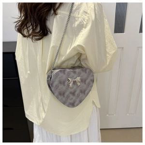 Detail of grey heart-shaped PU leather crossbody bag with silver bow and chain strap