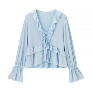 Detail of light blue V-neck top with ruffle trim, double bow ties, and flared sleeves