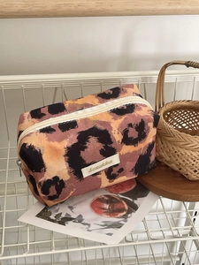 Detail of retro leopard print makeup bag with durable metal zipper and logo patch