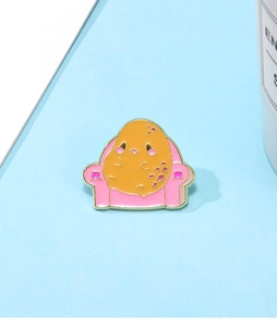 Détail d'un pin's en émail avec un personnage de nourriture jaune sur un fauteuil rose