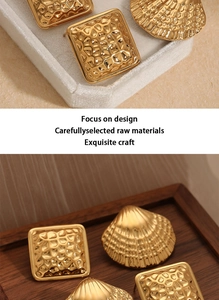 Close-up of golden geometric earrings showing hammered texture and shell motif details