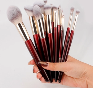 Detailed view of 15-piece professional makeup brush set with red handles and gold ferrules