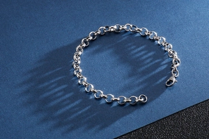 Macro view of silver Rolo chain bracelet with lobster clasp on a blue textured surface