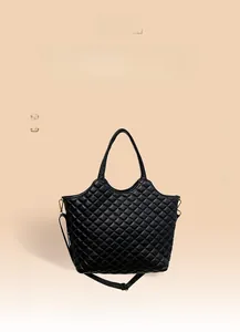 Detail of black quilted tote bag with glossy finish and adjustable shoulder strap