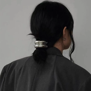 Silver metal minimalist ponytail hair clip shown on a low ponytail with sleek hair texture