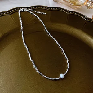 Silver bead fringe heart necklace with a round white pearl on a vintage tray