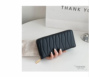 Detail of black long PU leather wallet featuring wavy quilted texture and gold zipper