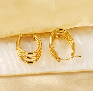 Macro detail of triple-layered 18k gold-plated hoops on elegant satin background