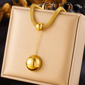 Detail of gold-plated mesh chain necklace with spherical pendant on a jewelry box